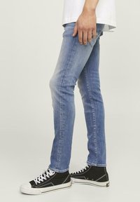 Heledad helesinine slim-fit teksapüksid, mis on valmistatud denimist, sisaldavad peent fade'i ja kontrastseid õmblusi, koos mustade kõrge ülaosaga tossudega.