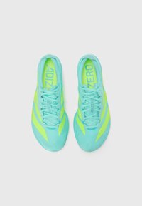Light blue athletic shoes with neon yellow accents and laces. Features sleek, streamlined design with textured upper and bold branding.