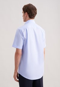 Koszula z krótkim rękawem w jasnoniebieskim kolorze z klasycznym kołnierzykiem. Gładka faktura, lekko zaokrąglony dół, przeszycia na tyle oraz minimalistyczny design.