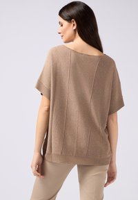 Maglietta in maglia marrone, a vestibilità ampia e maniche corte, con una finitura testurizzata e una leggera lucentezza. Collo rotondo e orlo a coste.