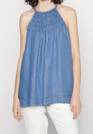 Top halter in denim blu chiaro con collo smock e vestibilità ampia. Presenta un orlo dritto e una sottile trama verticale.