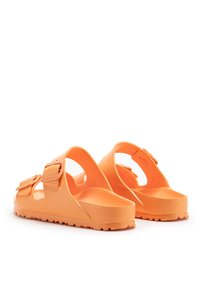 Sandalias naranjas hechas de goma duradera con una superficie texturizada, correas ajustables, lados recortados y una plantilla contorneada.