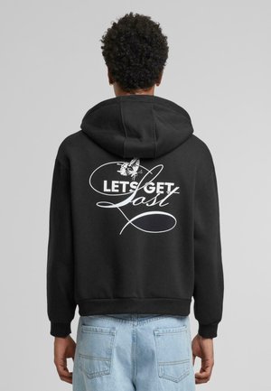 Schwarzer Hoodie mit großem weißen Grafiktext "LASS UNS VERLOREN GEHEN" und einem Schmetterlingsdesign, aus weichem Stoff, mit lockerer Passform und Kängurutasche.