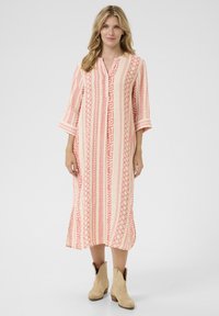 Rochie cu nasturi, cu model în roz deschis și crem, având desene geometrice, mâneci până la trei sferturi și o siluetă lungă, dreaptă.