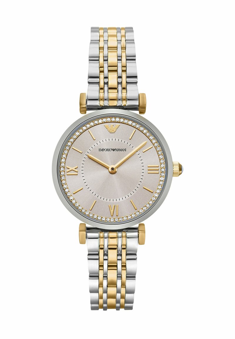 Dwutonowy metalowy zegarek z srebrno-złotą bransoletą. Okrągła srebrna tarcza ozdobiona kryształami. Rzymskie cyfry na 6 i 12, złote wskazówki.