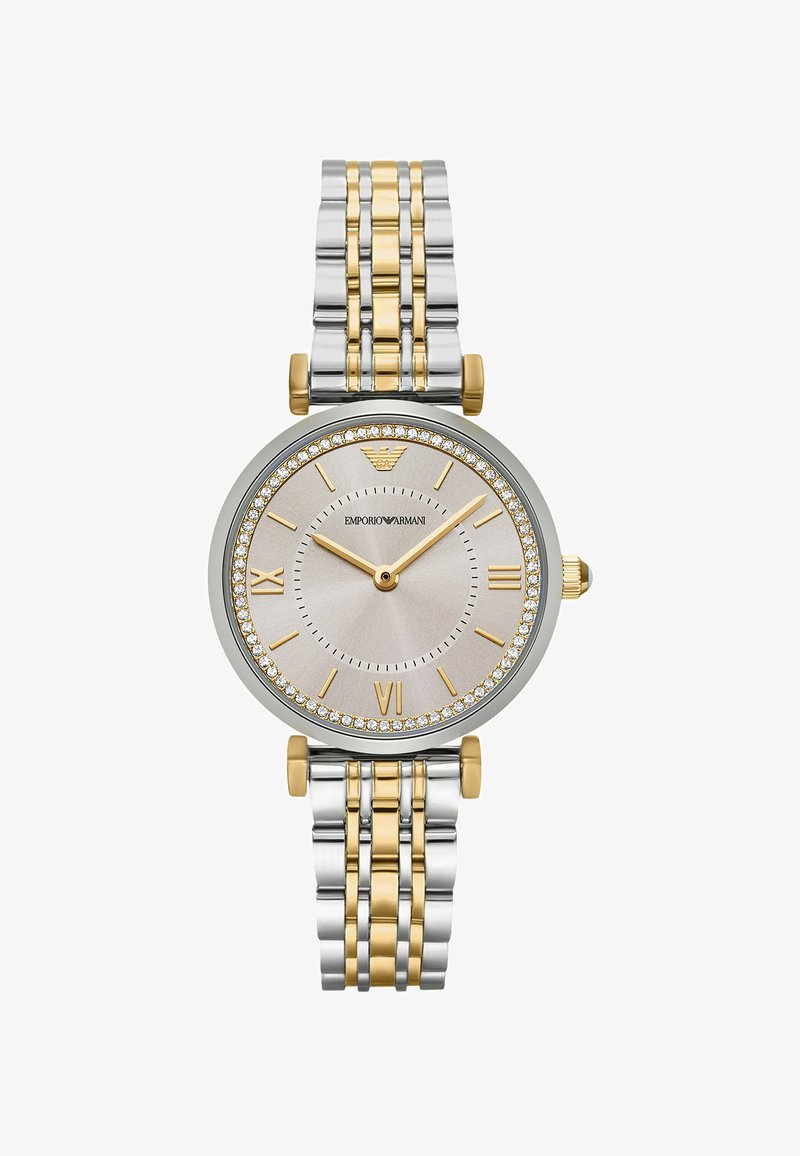 Tvåfärgad metallklocka med ett silver- och guldarmband. Rund silverfärgad urtavla prydd med kristaller. Romerska siffror vid 6 och 12, guldvisare.