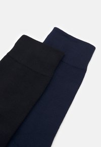 Due paia di calze: una nera e una blu scuro. Entrambe presentano un bordo a costine e sono realizzate in un morbido materiale di maglia testurizzata.