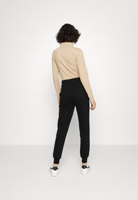 NA-KD PAMELA REIF x NA-KD - TRACKSUIT BOTTOMS - Calças de fato de treino - black