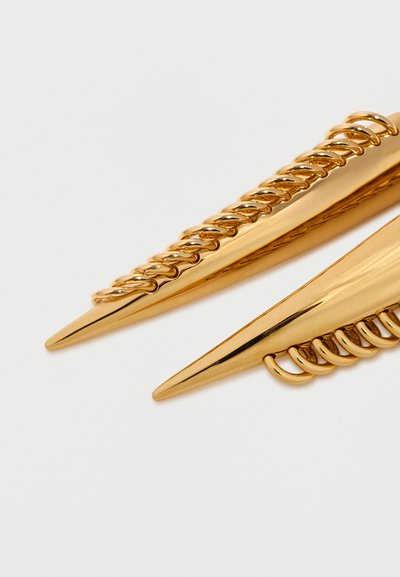 Δύο χρυσά κοκκαλάκια με μυτερό σχήμα και λεπτομέρειες από στριφτές αλυσίδες σε λευκό φόντο.