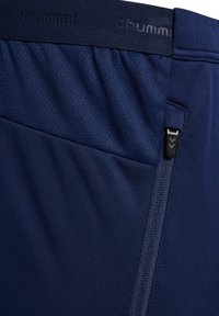Marina idrottsshorts med en texturerad midja, med en sidoficka med dragkedja och varumärket "hummel" präglat på midjan.