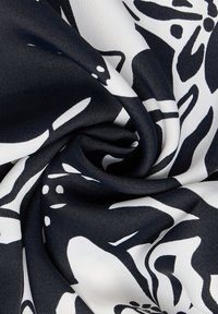 Marineblaue und weiße Stoffe mit einem floralen Muster, gefertigt aus glattem Material mit leicht glänzender Textur, angeordnet in einem wirbelnden Design.