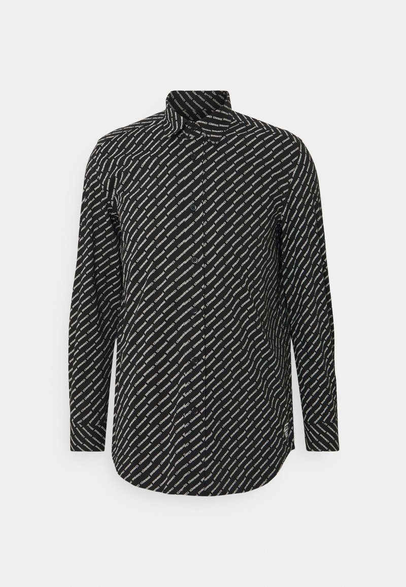 Chemise noire à boutons avec manches longues comportant un motif de texte blanc en diagonale répétée sur le tissu.