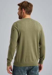 Olivno zeleni pulover z dolgimi rokavi, okroglim izrezom, rebrastim robom in detajli na rami. Mehka tekstura, prilegajoč dizajn. Priložnostni slog.