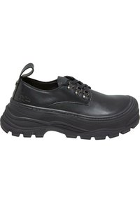 Chaussure en cuir noir avec une semelle en caoutchouc épaisse, bout rond et un design à lacets avec œillets métalliques et une petite languette à l'arrière.