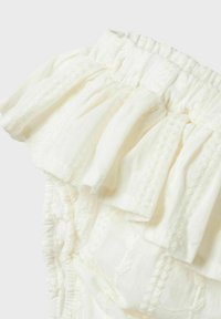 Tissu blanc avec des volants froncés et des rayures texturées. La taille élastique permet une flexibilité. Matière douce, couture détaillée et accents délicats.