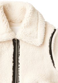 Gilet in pile color crema con materiale morbido e texturizzato. Presenta una chiusura a zip nera sul davanti e dettagli in pelle nera lungo le aperture delle braccia.