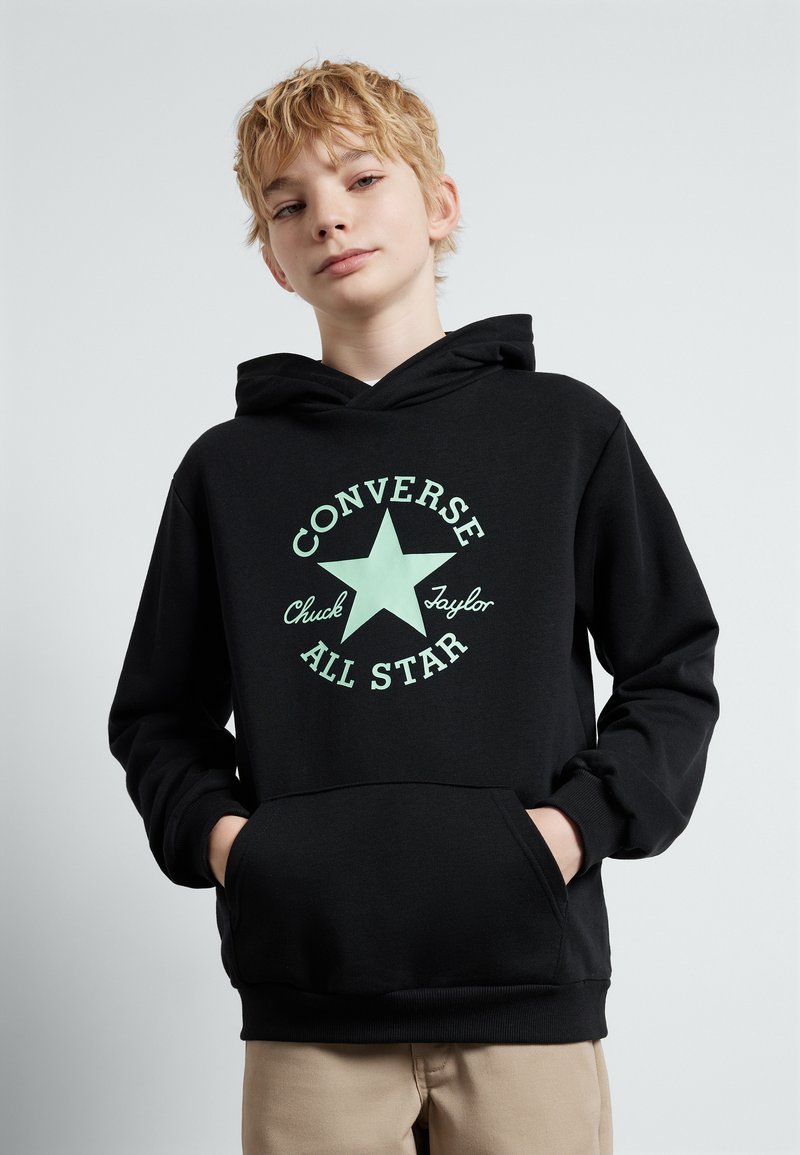Fekete kapucnis pulóver, menta zöld csillag grafikával, és a "Converse Chuck Taylor All Star" felirattal. Az elején zseb látható.
