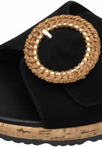 Černé semišové sandály s pleteným přírodním vláknem a zlatým kruhovým akcentem, s texturovanou korkovou podešví a plochým tvarem.