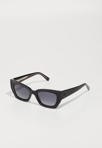 Black cat-eye sunglasses with gradient lenses, thick frames, and straight arms. Features a subtle logo on the temples.