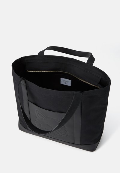 Bolsa de tote de lona negra con diseño de zorro en relieve en el frente, interior con cremallera y dos asas resistentes. Textura suave, diseño minimalista.