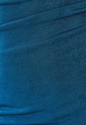 Tīklā zaļas audums ar ribotu tekstūru, kurā ir smalkas viļņošanās un savelšanās, kas rada dziļumu un dimensiju. Mīksts, elastīgs materiāls.