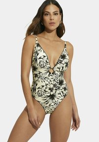 Maillot de bain une pièce de couleur crème avec un motif floral noir, présentant des bretelles réglables, un décolleté en V profond et un détail en forme de cercle.