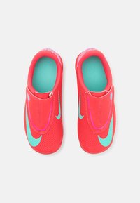 Červené nazúvacie topánky s textúrovaným povrchom, svetlomodrým interiérom a ružovými akcentmi. Obsahujú logá Nike swoosh po oboch stranách.