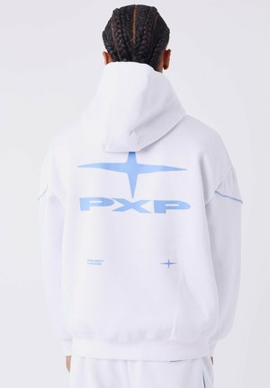 Persoon met gevlochten haar, die een witte hoodie draagt met een blauw "PXP"-logo en ster-symbolen op de achterkant, met de rug naar de camera gekeerd.