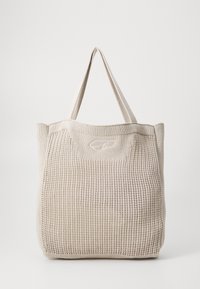 Beige strikket totebag med struktureret overflade, to solide håndtag og en subtil logo-detalje foran. Firkantet form til alsidig brug.