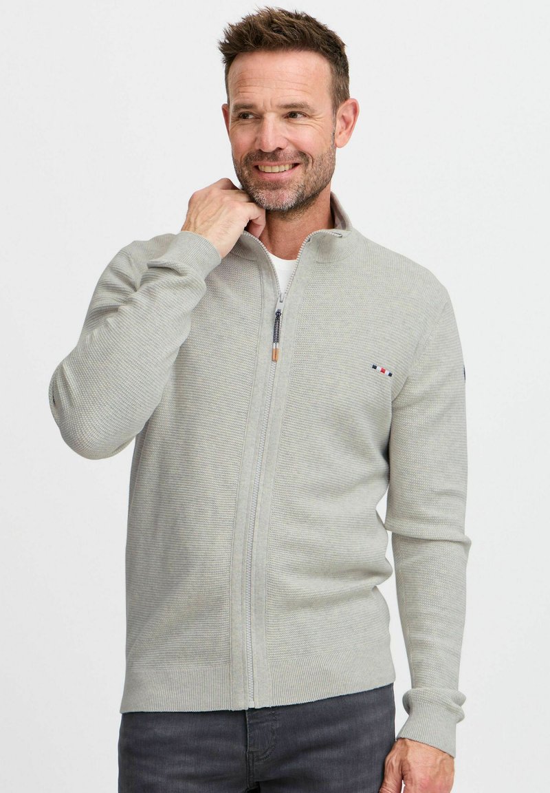 Hellgrauer Reißverschluss-Pullover mit strukturiertem Muster, gerippten Bündchen und Saum, mit einem kleinen Logo-Detail auf der Brust.
