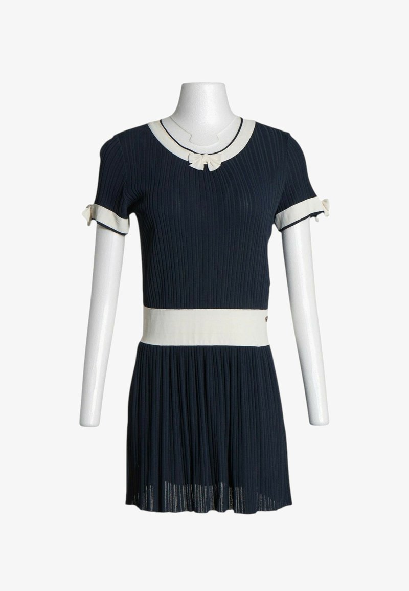 Robe côtelée bleu marine à manches courtes, bord blanc à l'encolure, à la taille et aux poignets, avec de petits nœuds blancs sur le col et les manches.