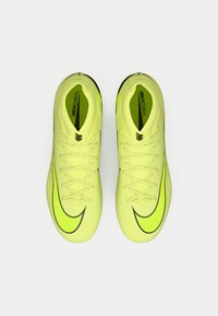 Spilgtas dzeltenas Nike Mercurial futbola kurpes ar teksturētu augšu, plāniem melniem akcentiem un tradicionālu šņorēšanu.