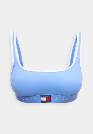 Bralette bleu clair avec bordure blanche, bretelles larges et bande élastique arborant le logo Tommy Jeans et un emblème de drapeau au centre avant.