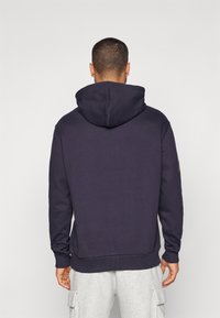 Marineblå hættetrøje med en stor baghætte, ribbede manchetter og kant, samt et minimalistisk design, lavet af blødt bomuldsstof.