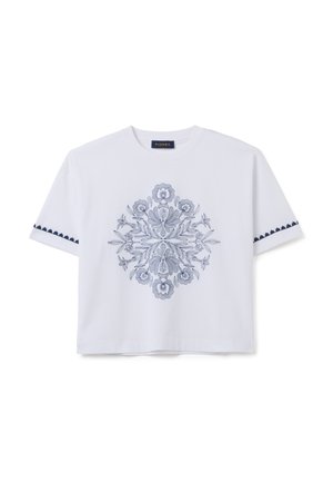 Camiseta de algodón blanca con un diseño de bordado floral azul en el centro y acentos decorativos en azul marino en las mangas.
