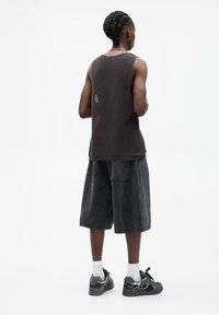 Débardeur en tricot gris foncé à finition texturée, associé à un short ample charbon et des baskets noires avec des accents blancs.