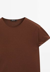 Brun kortærmet t-shirt lavet af blødt stof, med rund halsudskæring og minimalistisk design. Etiket synlig ved halsen.