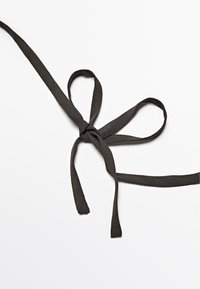 Sort tekstilbånd bundet i en sløjfe, med to lange, hængende ender og en glat, let struktureret overflade.