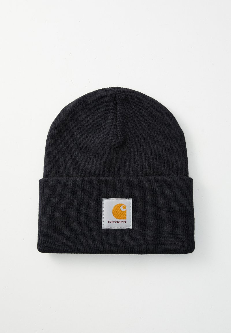 Black knitted beanie with a folded cuff, featuring a square white patch with a yellow logo and text "carhartt." Textured fabric, snug fit.