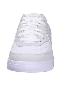 Zapatilla deportiva blanca con una parte superior de malla texturizada, acentos de ante y cordones planos. Presenta una suela de goma con una banda de rodadura con patrón para mayor tracción.