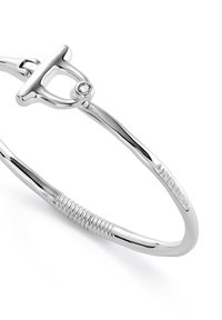 Bracelet en argent avec fermoir T-bar, doté d'une petite pierre précieuse transparente et d'une texture torsadée sur un côté.