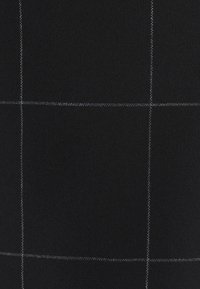 Svart tyg med rutmönster och vita sömmar. Strukturen verkar slät och tät, vilket gör det lämpligt för kläder eller klädsel.