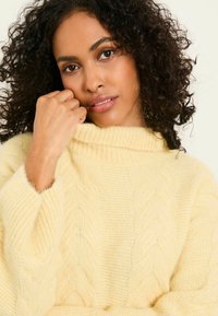 Helles gelbes, kabelgestricktes Sweatshirt mit hohem, geripptem Kragen und oversized Passform. Weiche Textur und lockere Ärmel sorgen für Komfort und Wärme.