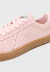 Sapatilha rosa claro com superfície texturada em relevo, atacadores planos e sola de borracha natural. Apresenta logo em relevo na lateral.