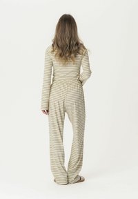 Striped jumpsuit in beige and green, featuring long sleeves, elastic waistband, and wide-leg design. Soft fabric and casual fit.