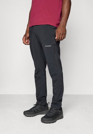 Black outdoor pants feature a slim fit, multiple pockets, and a logo on the thigh. Paired with black hiking shoes.