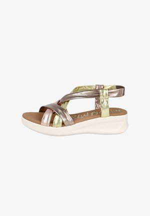 Sandalias de tiras metálico bronce y oro con plantilla acolchada marrón, suela blanca de plataforma y textura suave y lisa.