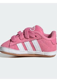 Růžová semišová bota s bílým designem tří pruhů, kulatou špičkou a růžovými tkaničkami. Vybavena gumovou podrážkou a polstrovaným límcem pro pohodlí.