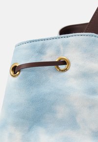 Sac en tissu bleu clair avec des motifs de nuages blancs, cordon en cuir marron passé à travers des œillets dorés gravés "PINKO".