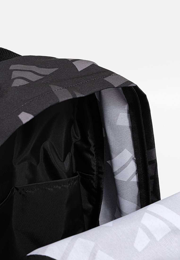 Intérieur d'un sac à dos noir avec des motifs géométriques gris. Présente une texture lisse, une poche latérale et un doublage contrasté en gris clair.